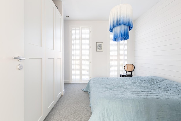 Lámpara de araña blanca y azul moderna y elegante en un dormitorio espacioso y moderno con cama king size