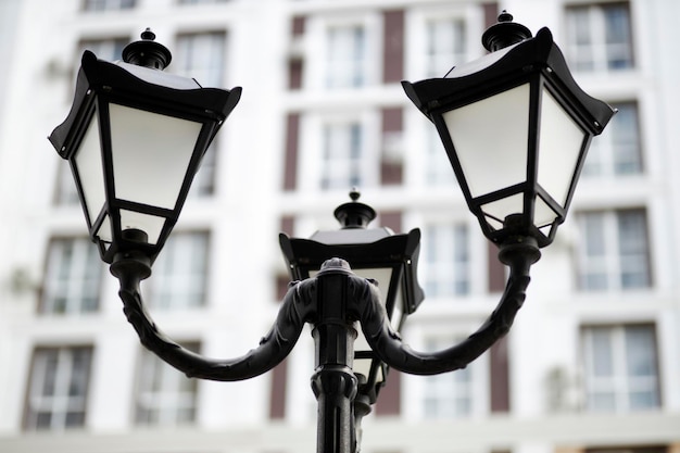 Lámpara de calle de acero vintage Una lámpara de calle retro se encuentra en un acogedor patio de la ciudad con edificios modernos