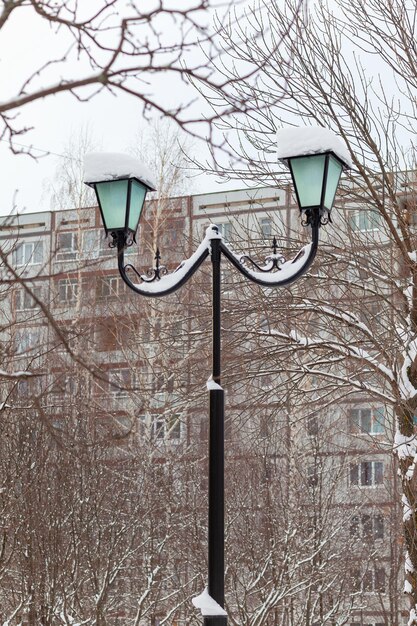 Lámpara de calle en el parque de invierno. Casa de vecindad en el fondo