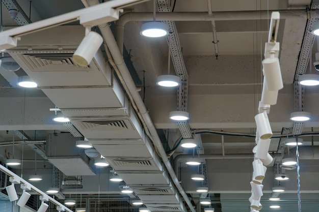 Lámpara colgante redonda en el techo blanco de la oficina y aberturas del sistema de ventilación Diseño interior en la oficina Una lámpara fluorescente en un techo suspendido moderno