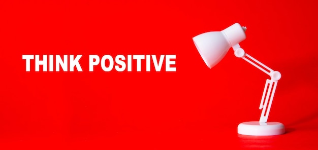 Lámpara de escritorio con palabra THINK POSITIVE sobre fondo rojo.