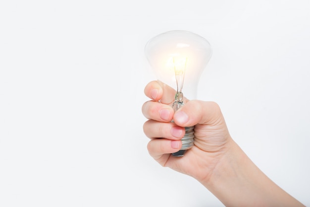 Lámpara incandescente brillante en la mano de un niño sobre un fondo claro