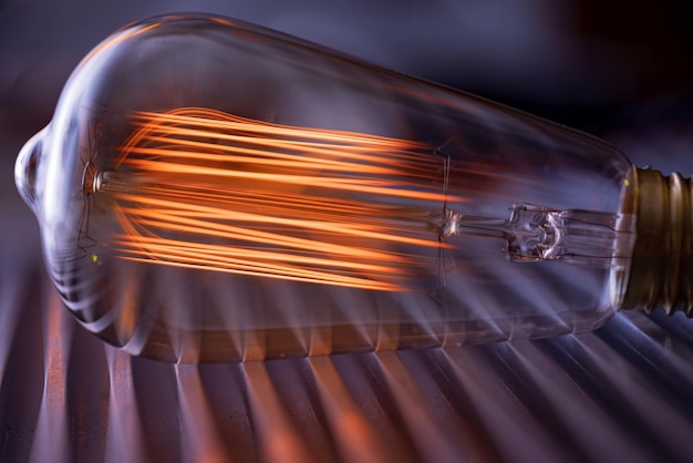 Una lámpara incandescente de vidrio potente y brillante ilumina una habitación oscura con una luz naranja ardiente