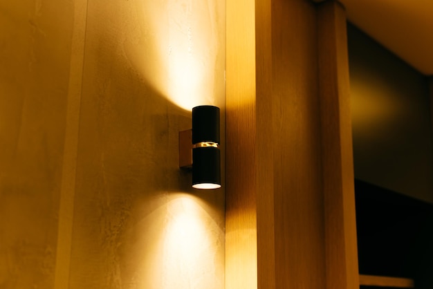 Lámpara negra cálida en una hermosa pared de madera. Luz indirecta.