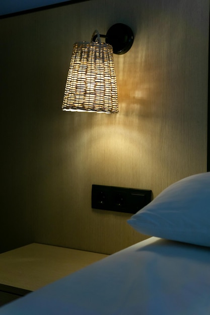 Lámpara de noche iluminando la mesita de noche y el lado más cercano a la cama concepto decoración y hoteles