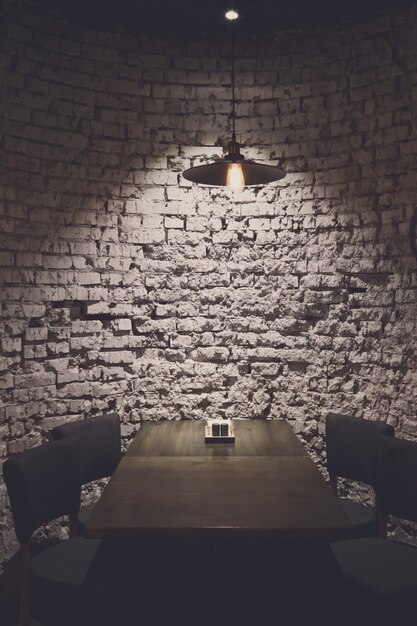 Foto lámpara de pared y techo de ladrillo grunge, sobre la mesa. fondo gris rugoso, bombilla colgante ilumina el comedor, interior del restaurante grunge