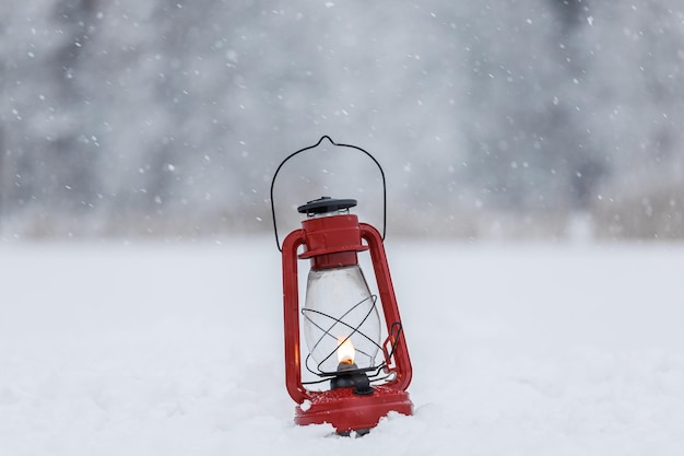 Una lámpara de queroseno roja arde en el bosque sobre la nieve.