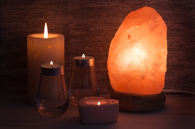Lámpara de sal del Himalaya con velas en una habitación oscura. Spa, relajarse concepto.