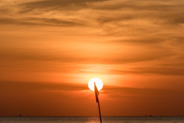 Foto lámpara de silueta por el mar contra el cielo durante la puesta de sol