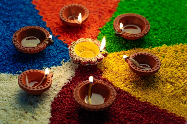 Lámparas de aceite encendidas en rangoli colorido o arroz durante la celebración de diwali