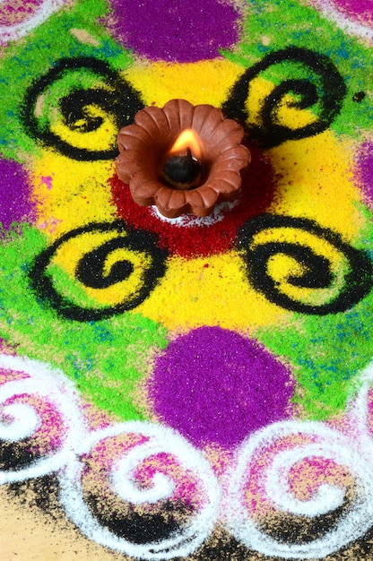 Lámparas de arcilla diya encendidas durante la celebración de diwali, Rangoli en segundo plano.