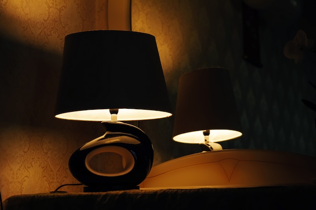 Lampe auf einem Nachttisch neben einem Bett