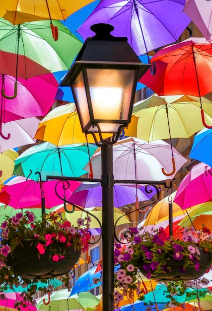 Lampe auf einer Straße mit Regenschirmen beleuchtet