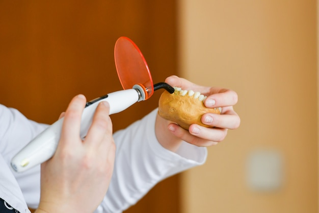 Lampe für Zähne. Zahnarzt mit Zahnbehandlung mit UV-Lampe an den Zähnen des Patienten. Gesunder Mund. Ein Stomatologe packt eine Scheinidentität mit einer Lampe ein