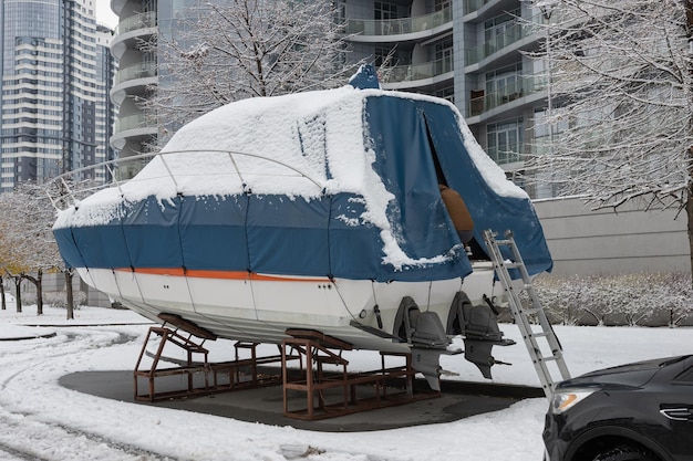 La lancha está cubierta con una cubierta y se encuentra al aire libre en la nieve Preparando el barco para el invierno