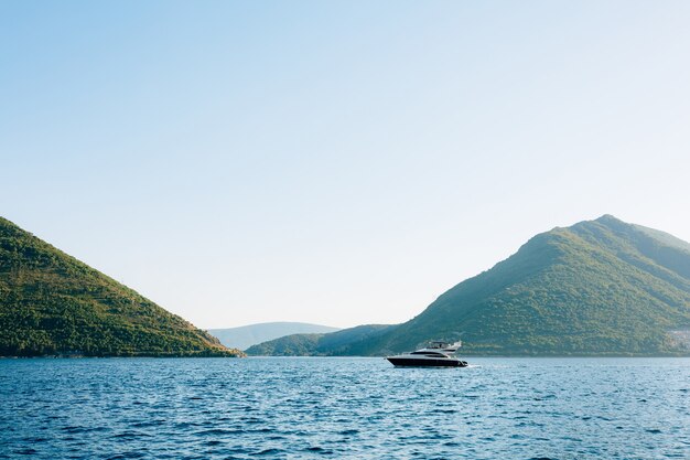 La lancha flota en el agua día cálido y soleado en la ciudad de perast