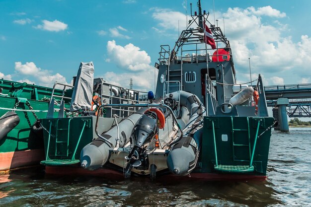 Foto lancha patrullera naval amarrada en el muelle de la ciudad con equipos industriales a bordo en un contexto de edificios urbanos y un cielo despejado