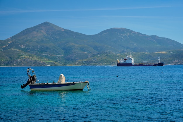 Lancha de pesca griega y carguero en el mar egeo, grecia