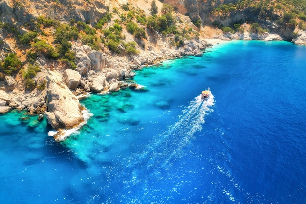 Lancha rápida en mar azul al amanecer en verano Vista aérea de lancha flotante en la bahía del mar Paisaje tropical con yate agua clara rocas piedras montaña árboles verdes Vista superior Oludeniz Turquía