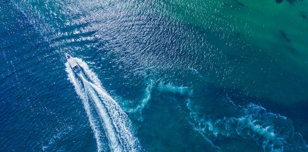 Una lancha rápida se mueve en círculo sobre la superficie del agua creando burbujas y olas