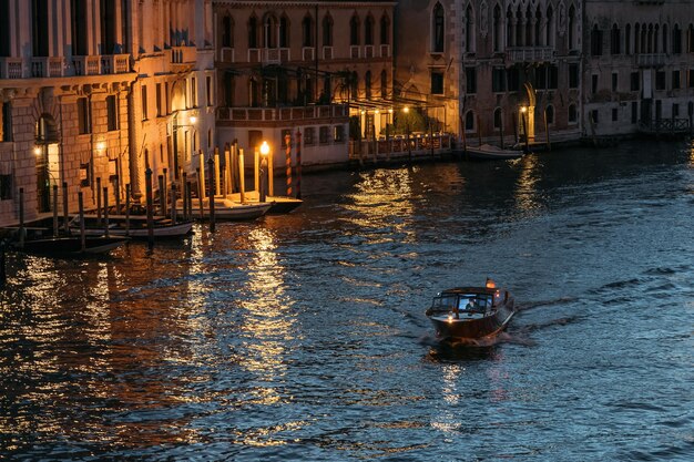 Lancha solitária flutua no grande canal de veneza em luzes brilhantes contra o pano de fundo da água azul