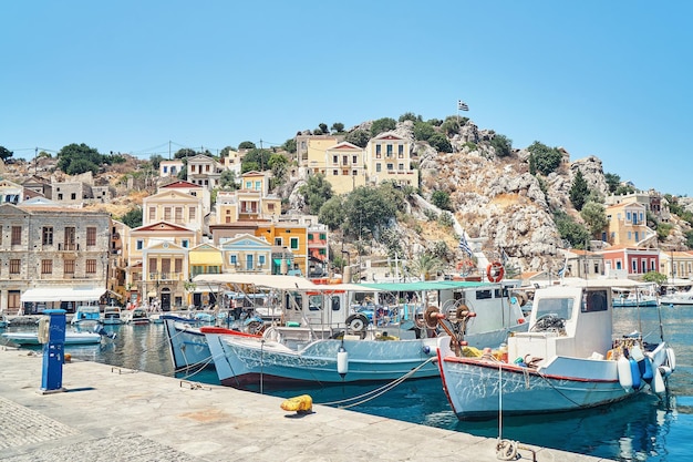Lanchas atracadas no mar azul contra a histórica cidade turística na Grécia, na ilha de Symi