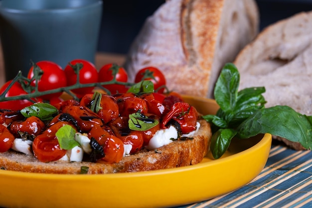 Foto lanche com uma fatia de pão de fermentação natural recheado com tomates confit mozzarella búfalo e uma chuva de redução de vinagre balsâmico com melaço de cana-de-açúcar