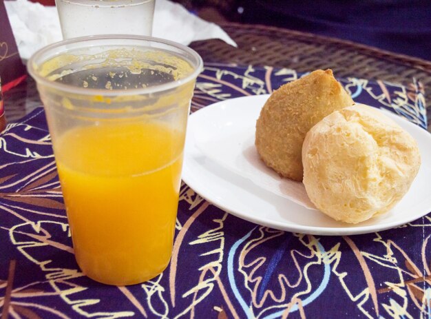 Lanche composto por suco de pão de queijo e bolinho típico brasileiro