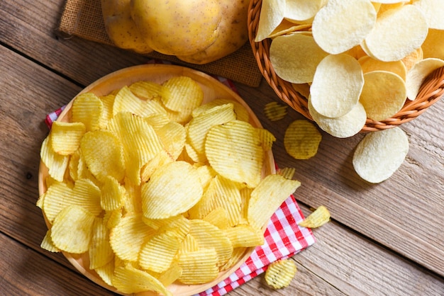 Lanche de batatas fritas no prato batatas fritas crocantes na mesa da cozinha e batatas cruas frescas na vista superior de fundo de madeira