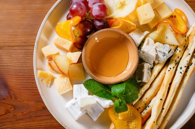 Lanche de frutas com croutons de queijo de uvas mel laranja e pera guarnecido com hortelã closeup