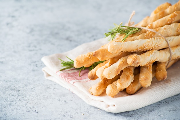 Lanche italiano tradicional grissini - breadsticks com azeite e sementes de gergelim em um fundo claro, copie o espaço