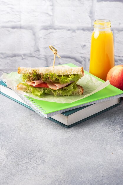 Lanche para a escola com sanduíche, maçã fresca e suco de laranja. material escolar colorido, espaço de cópia,