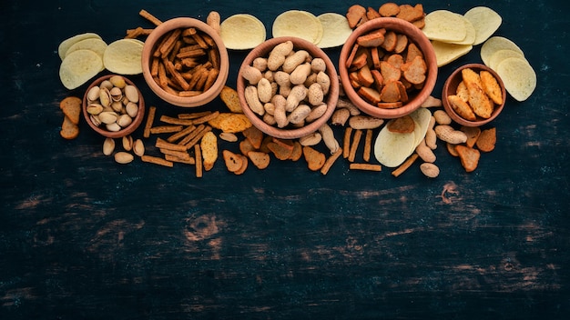 Lanche para cerveja biscoitos salgados batatas fritas nozes amendoim pistache em um fundo de madeira espaço livre para texto vista superior