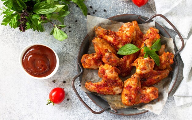 Lanche saboroso asas de frango assado com molho de mostarda e tomate em uma mesa de concreto