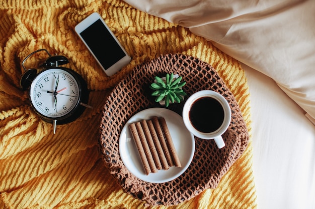 Lanche saboroso e uma xícara de café no café da manhã com relógio marcando 7 horas na cama