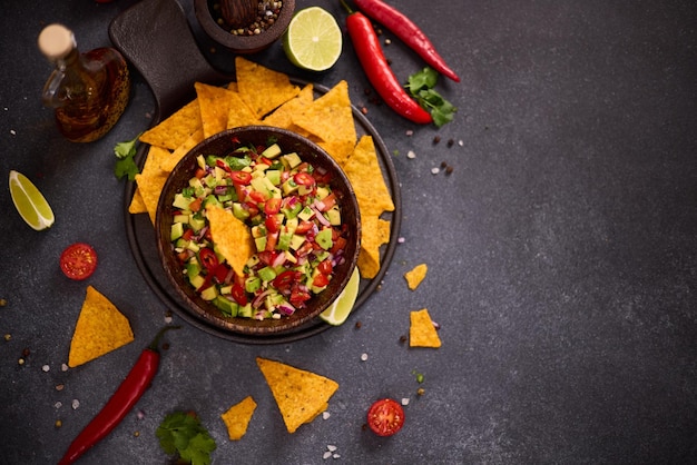 Lanche tradicional de salsa em uma tigela de madeira e batatas fritas de milho em uma mesa com ingredientes