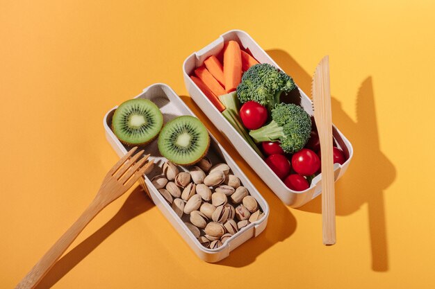 Lancheira com frutas e nozes de legumes frescos em fundo amarelo