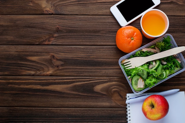 Lancheira com salada, notebook e telefone