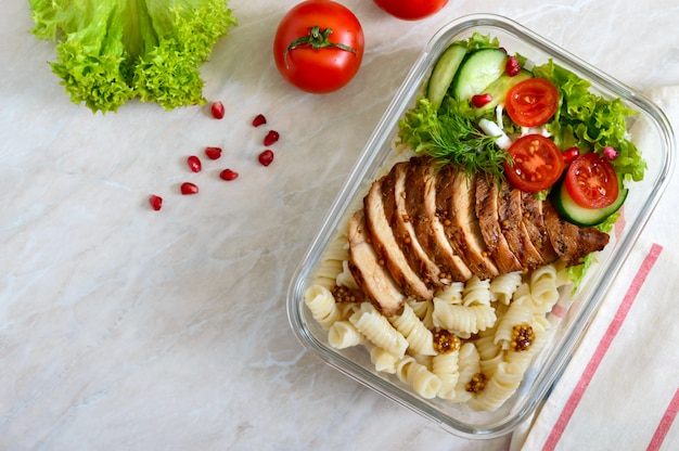 Lancheira: rotini com peito de frango assado e salada. vista superior, plana leigos. delicioso almoço saudável.