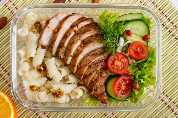 Lancheira: rotini com peito de frango assado e salada. Vista superior, postura plana. Delicioso almoço saudável. O conceito de alimentação saudável.