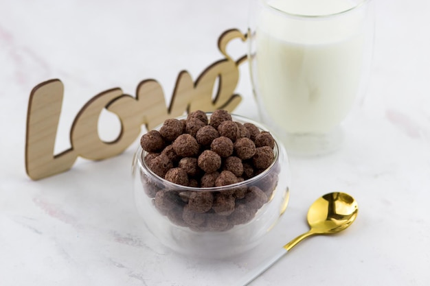 Lanches em forma de bolas de chocolate Uma tigela com um café da manhã rápido um copo de leite e a inscrição amor em um fundo de mármore branco