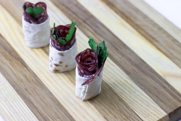 Foto lanches festivos em uma tábua de madeira aperitivos com salsicha e queijo creme