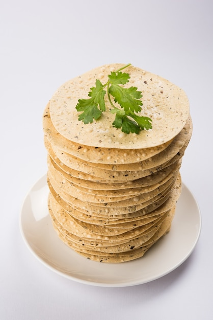 Lanches indianos, pilha de biscoitos Mung Urad dal ou papad fritos ou assados, que é um acompanhamento no almoço e no jantar. Servido em cesto de cana ou prato com folha de coentro.