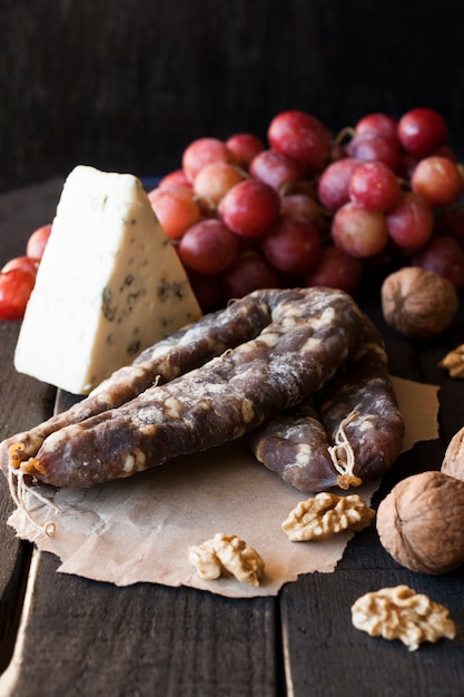 Lanches para vinho, queijo com mofo, uvas rosadas, nozes e salsicha seca