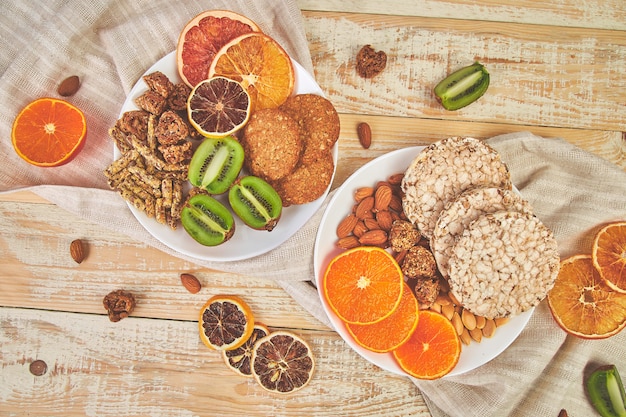 Foto lanches saudáveis - variedade de barra de granola de aveia, batatas fritas de arroz, amêndoa, kiwi, laranja seca