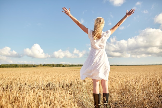 Land-, Natur-, Sommerferien-, Urlaubs- und Menschenkonzept - glückliche junge Frau im weißen Kleid auf dem Getreidefeld