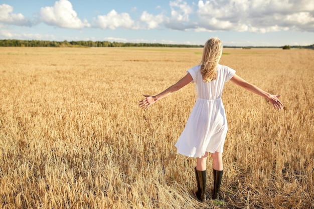 Land-, Natur-, Sommerferien-, Urlaubs- und Menschenkonzept - glückliche junge Frau im weißen Kleid auf dem Getreidefeld