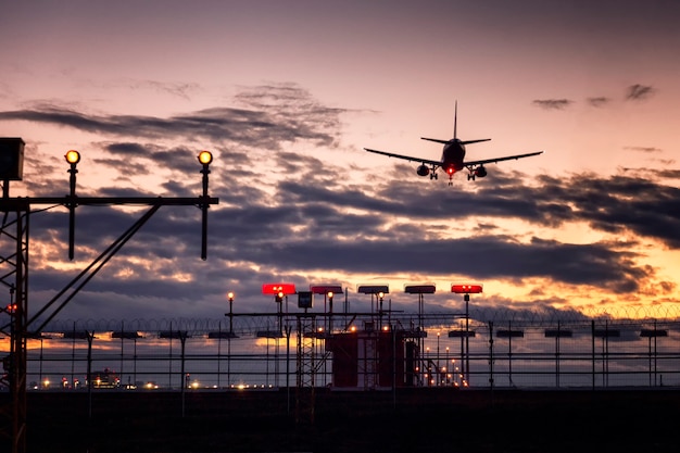 Landeflugzeug und Wünschelruten-Vogelschrecken am Flughafen gegen schönen rosa Sonnenuntergang.