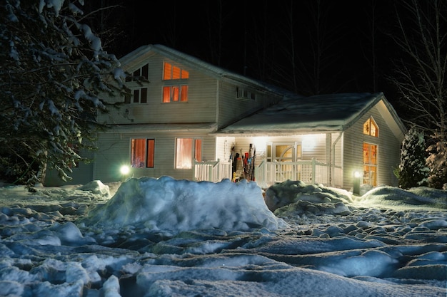 Landhaus mit Licht in den Fenstern in einer verschneiten Winternacht