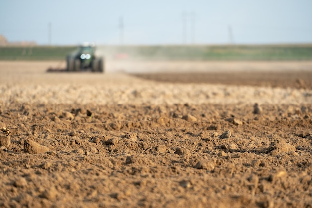 Landmaschinen arbeiten auf dem Feld Ein Traktor mit Pflug bewirtschaftet das Land vor der Aussaat von Weizen und anderem Getreide Weicher Fokus gepflügter Boden Nahaufnahme Leerer Platz zum Einfügen von Text